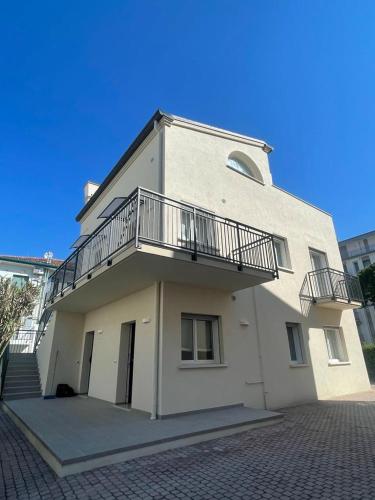 - un bâtiment blanc avec un balcon et des escaliers dans l'établissement VILLA EMMA -WALTERIGATO Apartments SOLO PER FAMIGLIE, à Lido di Jesolo