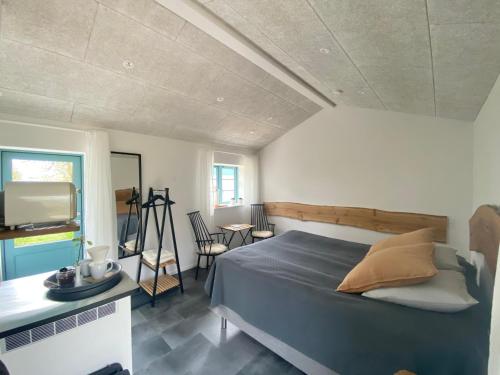 um quarto com uma cama, uma mesa e uma televisão em Tiny Guesthouse em Nakskov