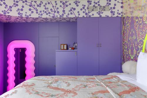 a bedroom with purple walls and a bed with a pink bedspread at Hotel De Witte Lelie -Small Luxury Hotels of the World in Antwerp
