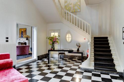 a living room with a staircase and a checkered floor at Small Luxury Hotel De Witte Lelie in Antwerp