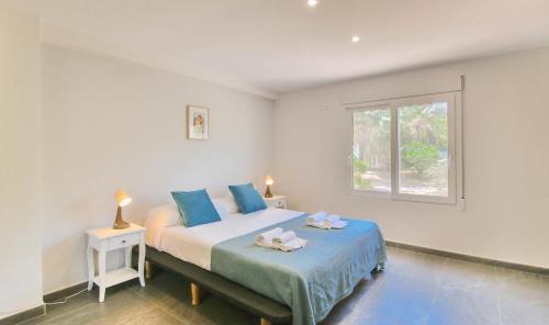 Un dormitorio con una cama con almohadas azules y una ventana en Las Rotas KD en Denia