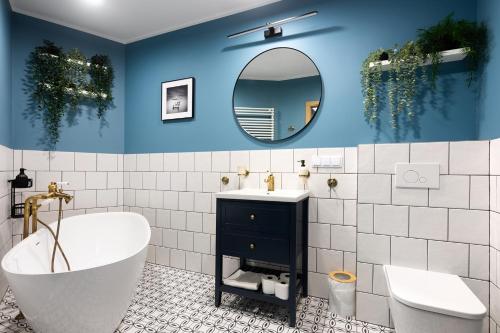 La salle de bains est pourvue d'une baignoire, d'un lavabo et d'un miroir. dans l'établissement Mary&Arte Apartments Grzegórzecka 15, à Cracovie