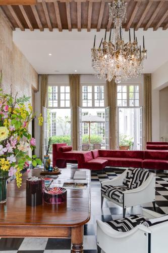 a living room with red furniture and a chandelier at Hotel De Witte Lelie -Small Luxury Hotels of the World in Antwerp