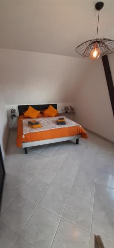 1 dormitorio con 1 cama con edredón de naranja en Le grenier de Véro, en Houssen