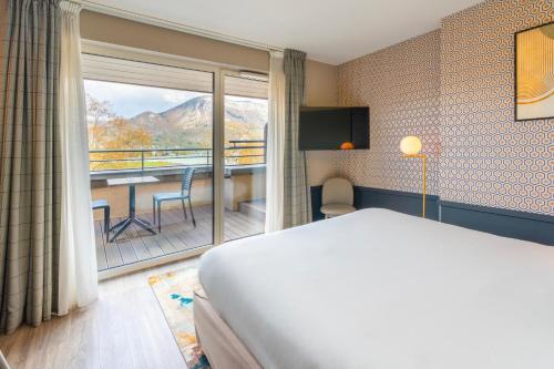 a hotel room with a bed and a balcony at Le Splendid Hotel Lac D'Annecy - Handwritten Collection in Annecy