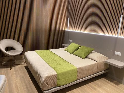 a bedroom with a bed with green pillows and a chair at Th Luxury Central in Catania