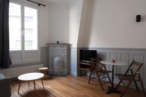 ein Wohnzimmer mit einem Kamin, einem Tisch und Stühlen in der Unterkunft Charming love nest near Montmartre in Paris