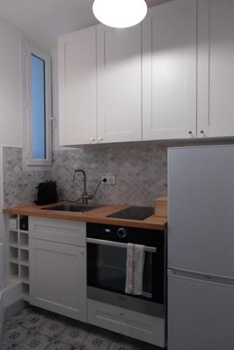 une cuisine avec des armoires blanches, un évier et une cuisinière dans l'établissement Charming love nest near Montmartre, à Paris