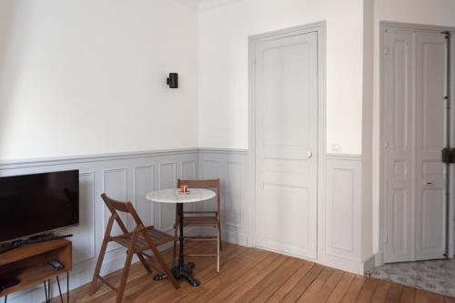 Zimmer mit einem Tisch und einem TV sowie einem Tisch und Stühlen in der Unterkunft Charming love nest near Montmartre in Paris