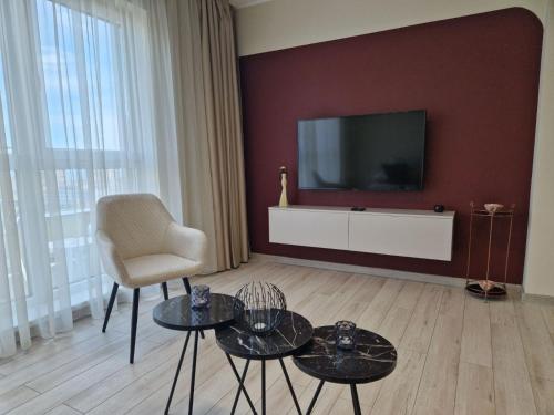 een woonkamer met een televisie, een stoel en tafels bij PAPAYA APARTMENTS in Varna