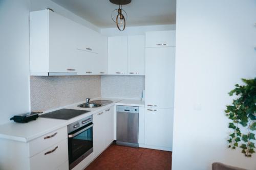 una cocina blanca con armarios blancos y fregadero en Apartment Golden - 2BR with Parking, Prime Location, en Pristina