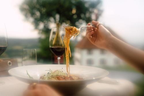 a person eating spaghetti on a plate with a glass of wine at Schloss Freudenfels in Eschenz