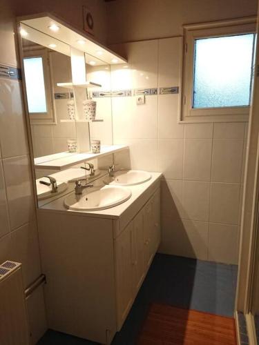 une salle de bain avec deux lavabos et un grand miroir dans l'établissement Maison d'altitude avec vue panoramique à Gérardmer, à Gérardmer