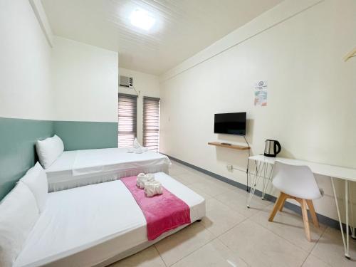 um quarto de hotel com duas camas e uma televisão em Verra Inn em Tagaytay