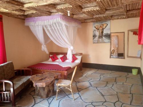 Habitación con cama, sofá y mesa. en Jambo Afrika Resort, en Emali
