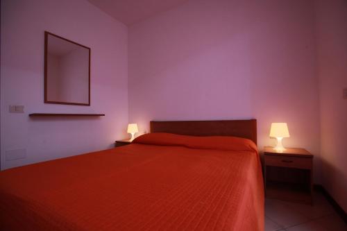 um quarto com uma cama laranja e 2 candeeiros em Beautiful villa with private garden and porch em Rosolina Mare