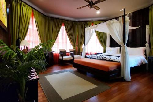 een slaapkamer met een hemelbed en een bank bij Tiara Golf Villa With Pool in Melaka