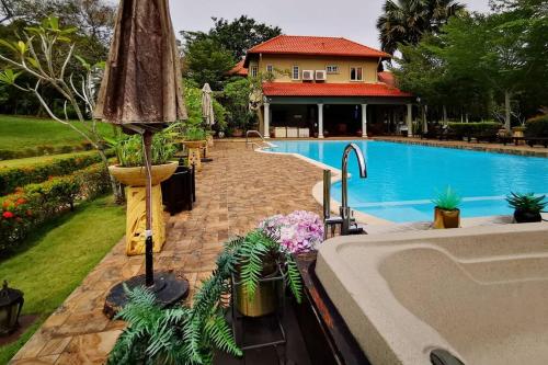 una piscina con sombrilla junto a una casa en Tiara Golf Villa With Pool, en Melaka