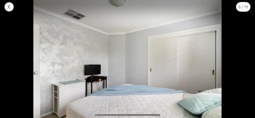 a white bedroom with a bed and a tv at Guest ensuite 7 minutes from airport in Melbourne