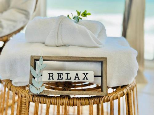 a basket with towels and a sign that says relax at Relax and Retreat at BellaView603 - Comfortable Oceanfront Condo in Daytona Beach