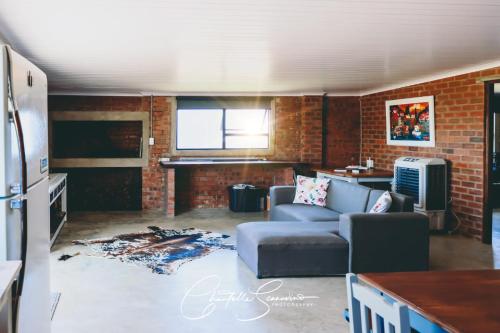 a living room with a couch and a brick wall at Oppi Plaas See Uitsig in Groot Brak Rivier