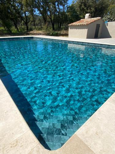 a swimming pool with blue tiles on the water at Magnifique villa avec piscine au coeur des vignes in Cogolin