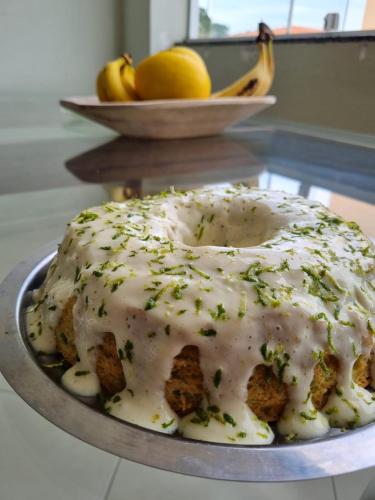 a cake with white icing on a plate on a table at Pousada Coqueiral in Aracruz