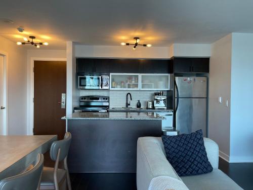 a kitchen and living room with a couch and a refrigerator at TORONTO SKYLINE VIEW CONDO LIBERTY VILLAGE (Private Room & Bath) in Toronto