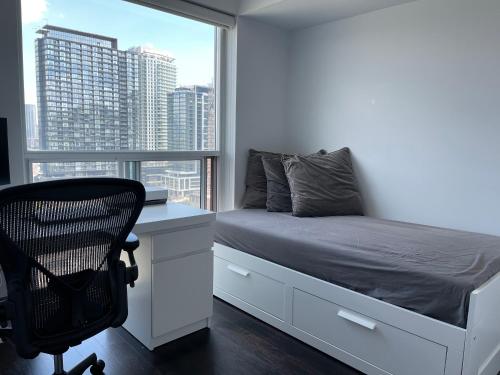 een slaapkamer met een bed, een bureau en een raam bij TORONTO SKYLINE VIEW CONDO LIBERTY VILLAGE (Private Room & Bath) in Toronto