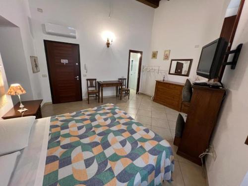 een slaapkamer met een bed en een televisie en een tafel bij L'Antica Torre Caralis Holiday in Cagliari