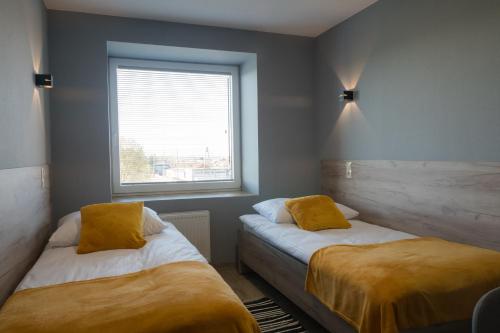 two beds in a room with a window at Hotel Pod Brzozą in Strzelce Opolskie