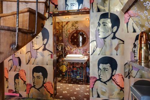 a bathroom with a wall covered in paintings of men at Small Luxury Hotel De Witte Lelie in Antwerp