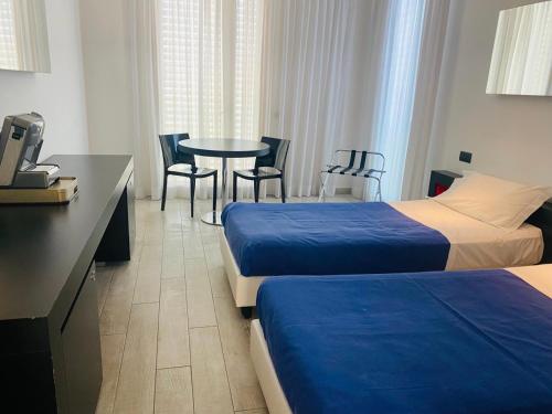 a hotel room with two beds and a table and chairs at Blue Shades ApartHotel in Pisa
