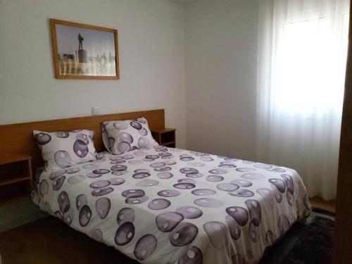 una camera da letto con un letto con un piumone viola e una finestra di Monte dos Pastorinhos a Fátima