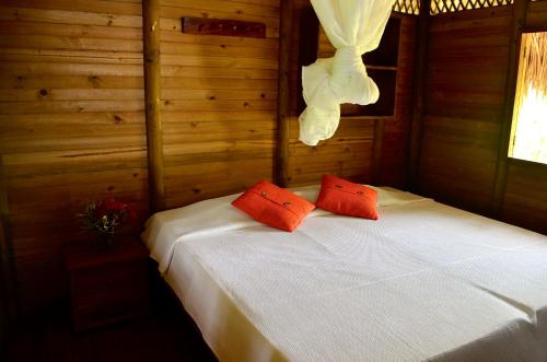Cabaña Wiwa Tayrona في سانتا مارتا: غرفة نوم بها سرير ووسادتين حمرا