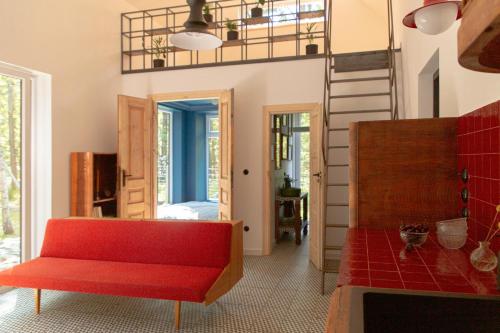 a living room with a red couch and a staircase at Tu, Tam i Tamten Domek in Wojtyniów