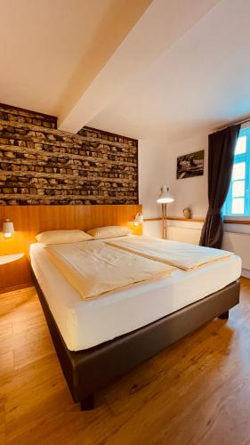 a large bed in a room with a brick wall at Salischer Hof in Schifferstadt