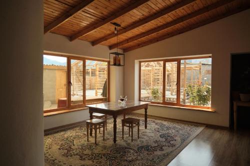 a dining room with a table and chairs and windows at Guest House Altyn Oimok in Bokonbayevo