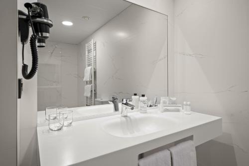 a white bathroom with a sink and a mirror at Hotel Zentral Ramiro I Oviedo in Oviedo