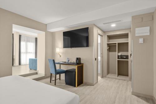 a hotel room with a bed and a desk and a television at Hotel Zentral Ramiro I Oviedo in Oviedo