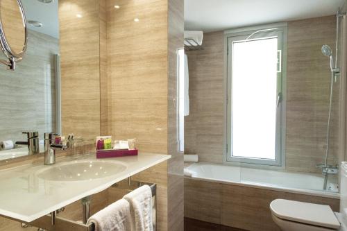 uma casa de banho com um lavatório, uma banheira e uma janela em Zenit Barcelona em Barcelona