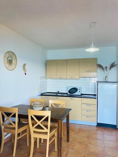 une cuisine avec une table, des chaises et un réfrigérateur dans l'établissement Punta di mare, appartements bord de mer, à Linguizzetta