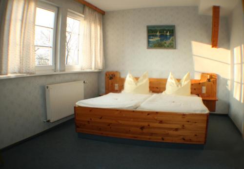 a bedroom with a wooden bed with white sheets and pillows at Landgasthof zur krummen Linde in Stolpe