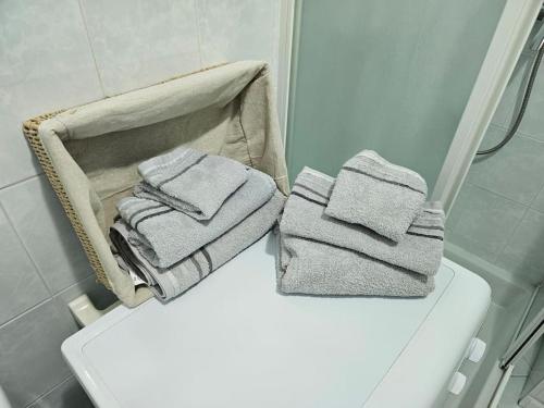 - une pile de serviettes assises au-dessus des toilettes dans la salle de bains dans l'établissement L'onda, cosy 2 pièces à Menton proches plages, à Menton