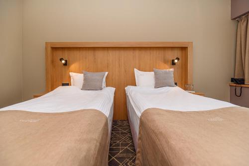 two beds in a hotel room with white sheets at HOTEL CENTRAL Pascani in Paşcani