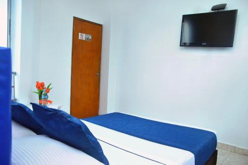a bedroom with two beds and a flat screen tv at Ayenda Hotel Roisa in Girardot