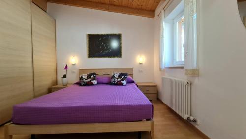 una camera con letto viola e finestra di Casa Elka Residence Lake view and pool by Garda Domus Mea a Pieve