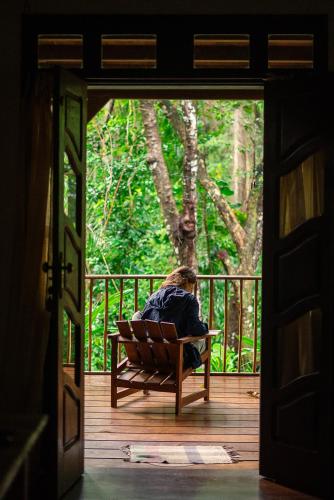 a person sitting on a bench on a porch at Anjali in Ilha de Boipeba