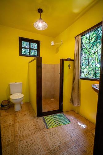 a yellow bathroom with a toilet and a shower at Anjali in Ilha de Boipeba