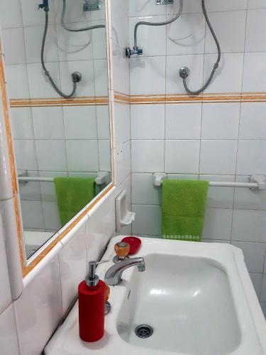 a bathroom with a sink and a mirror and green towels at Nomad Villa Santa Fe in Las Palmas de Gran Canaria